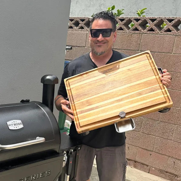 A customer carrying The True Board by its steel handles next to his smoker