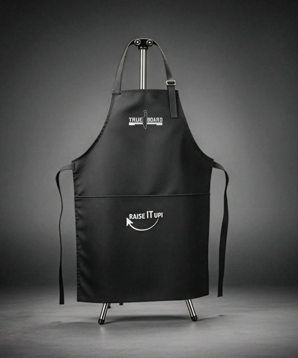 Black apron with 'True Board' and 'Raise It Up!' text on a gray background