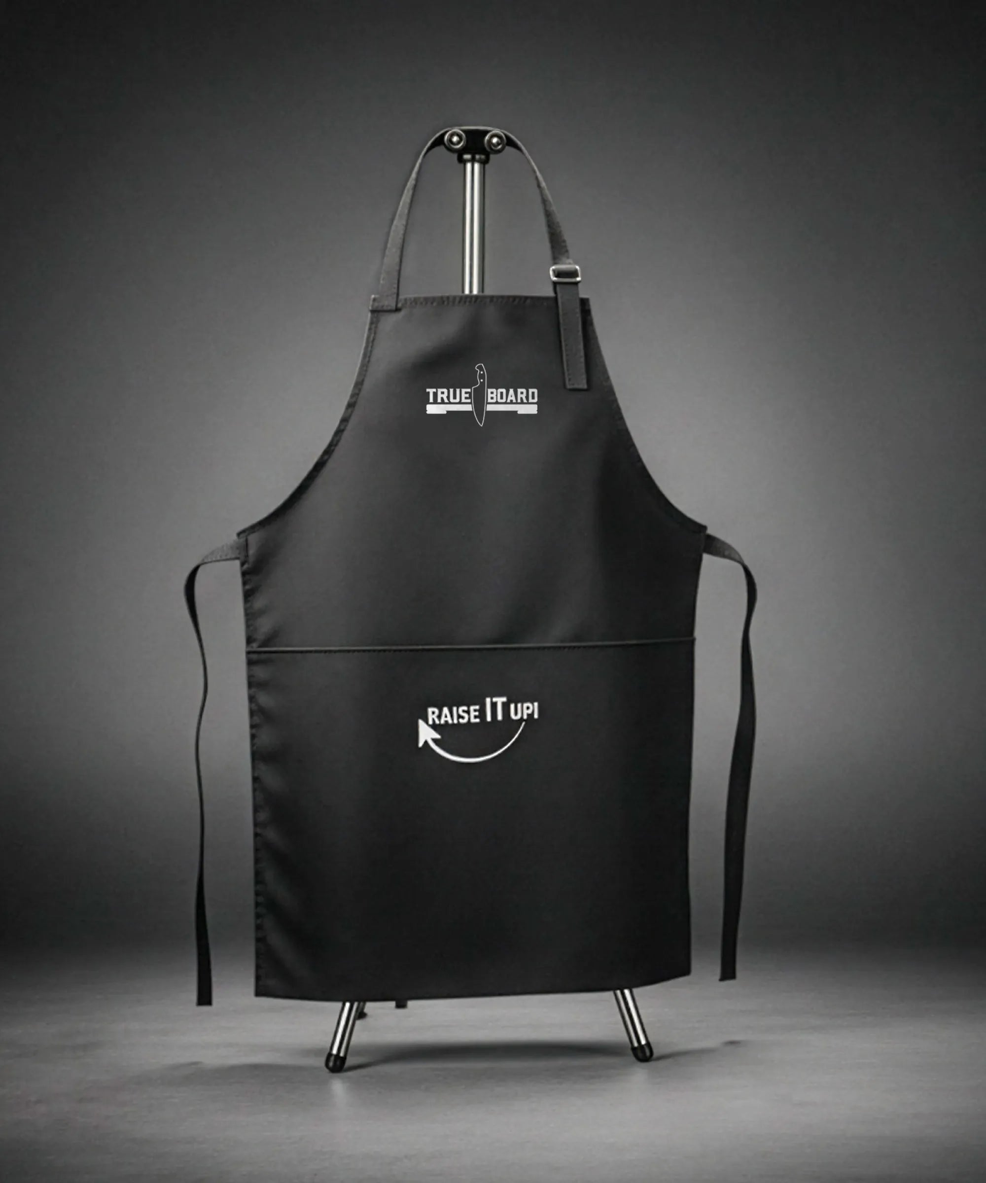 Black apron with 'True Board' and 'Raise It Up!' text on a gray background