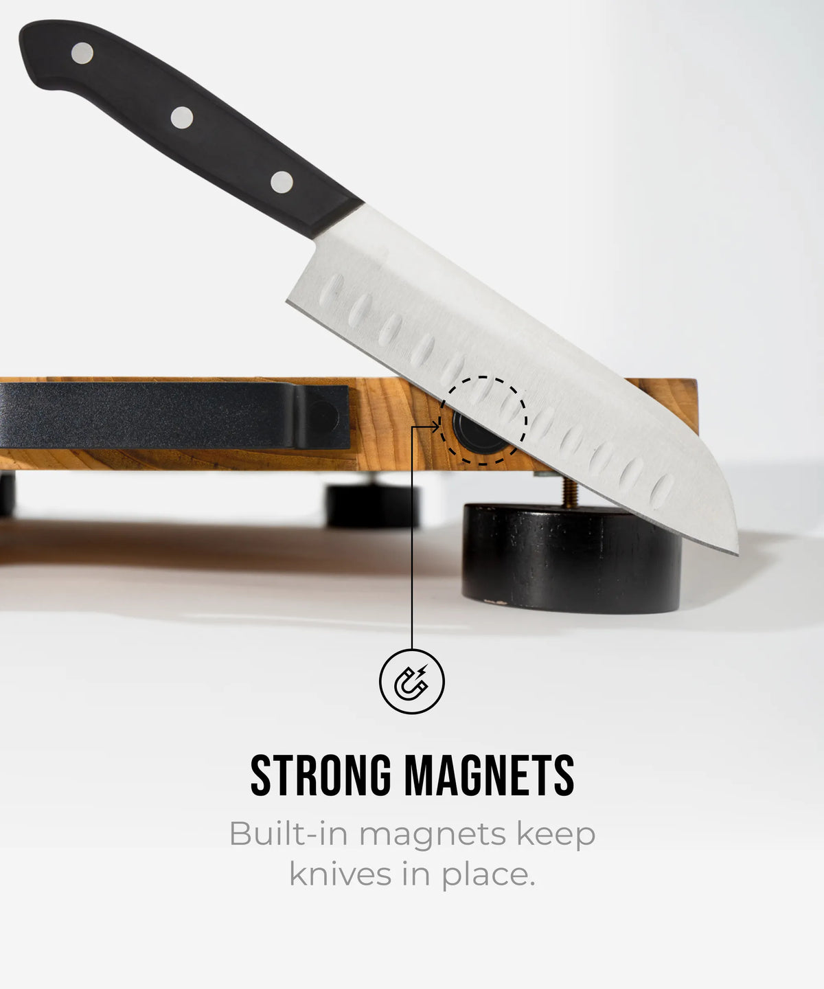 Knife with a black handle and white blade on a magnetic knife holder, with text highlighting built-in magnets.