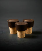 Three wine bottle corks with dark stoppers on a dark background