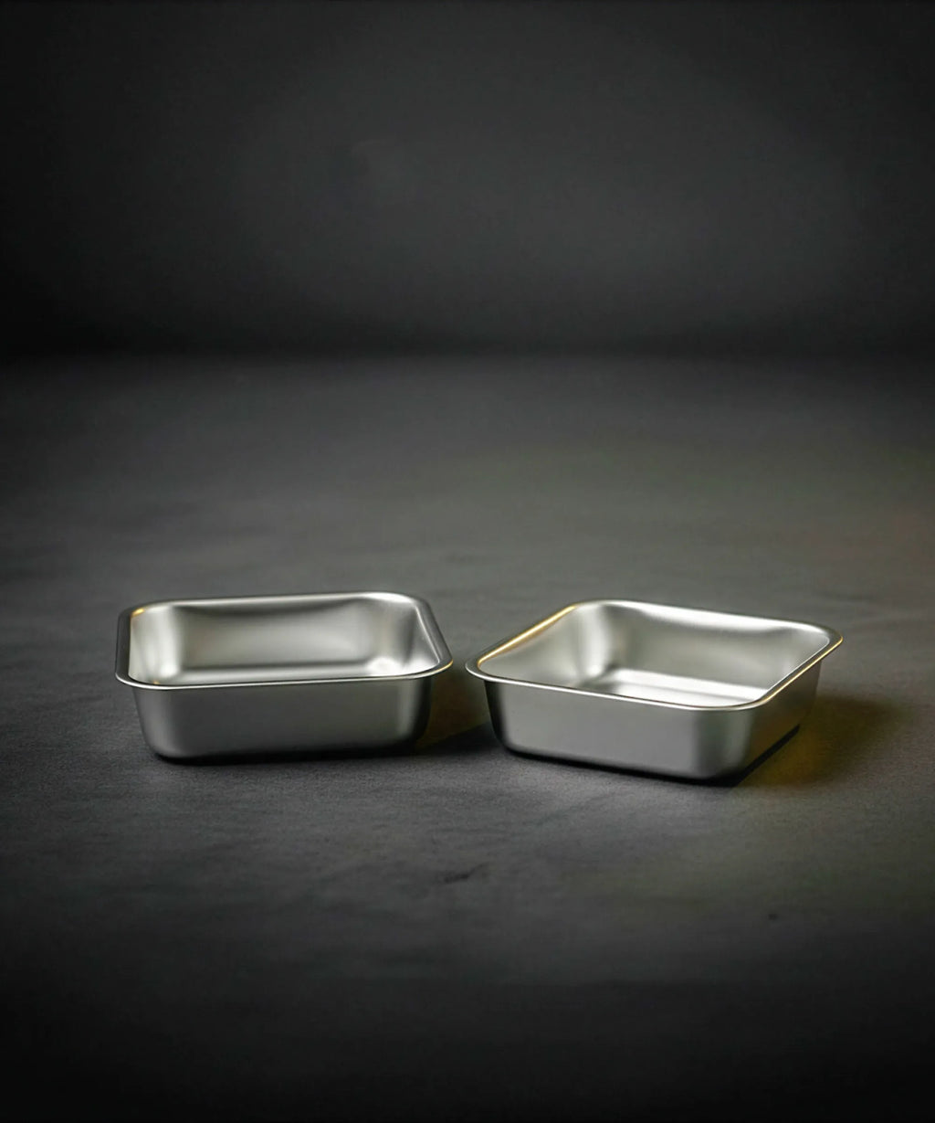 Two metallic baking trays on a dark gray background
