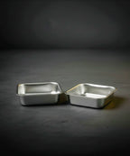 Two metallic baking trays on a dark gray background