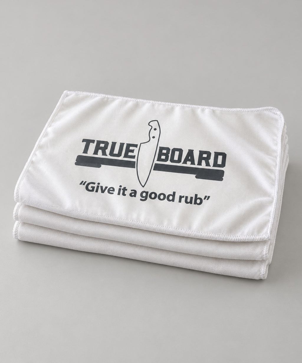 Three True Board towels folded and stacked, printed with the TRUE | BOARD logo