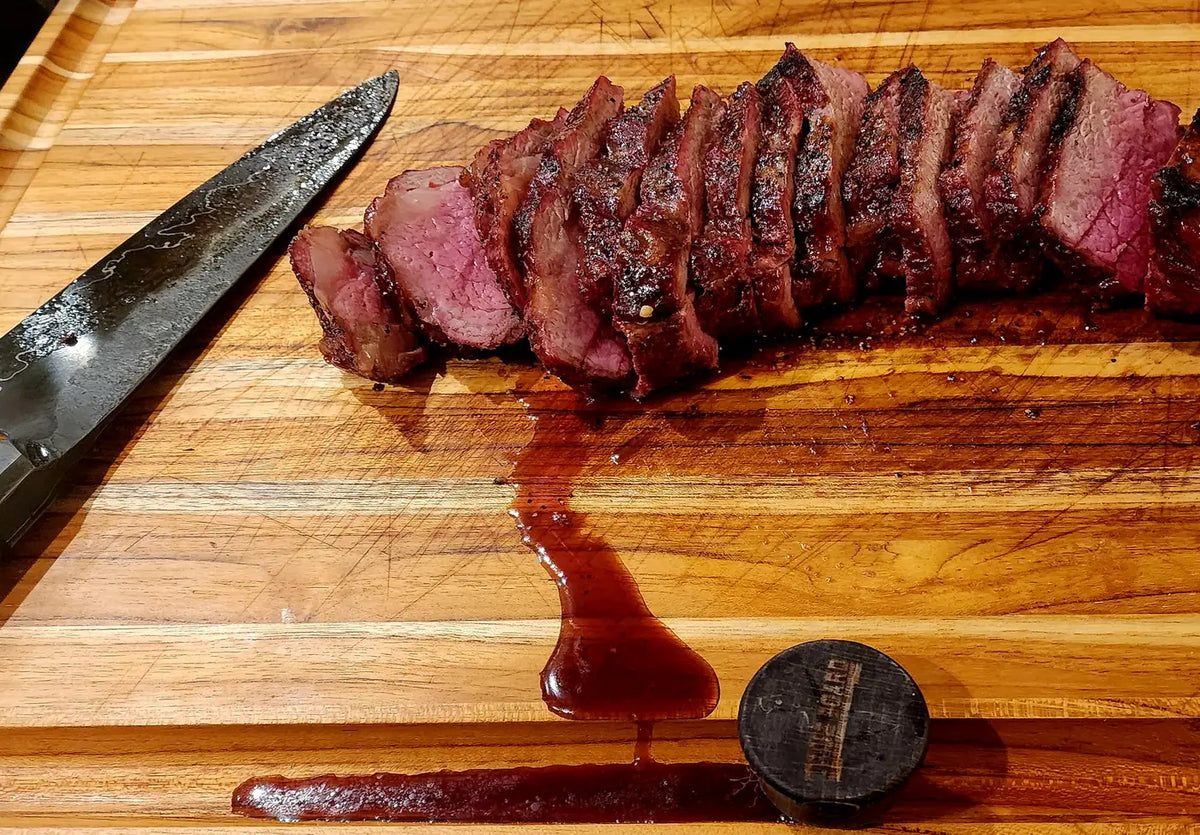 Sliced tri-tip resting on The True Board with juice in the groove
