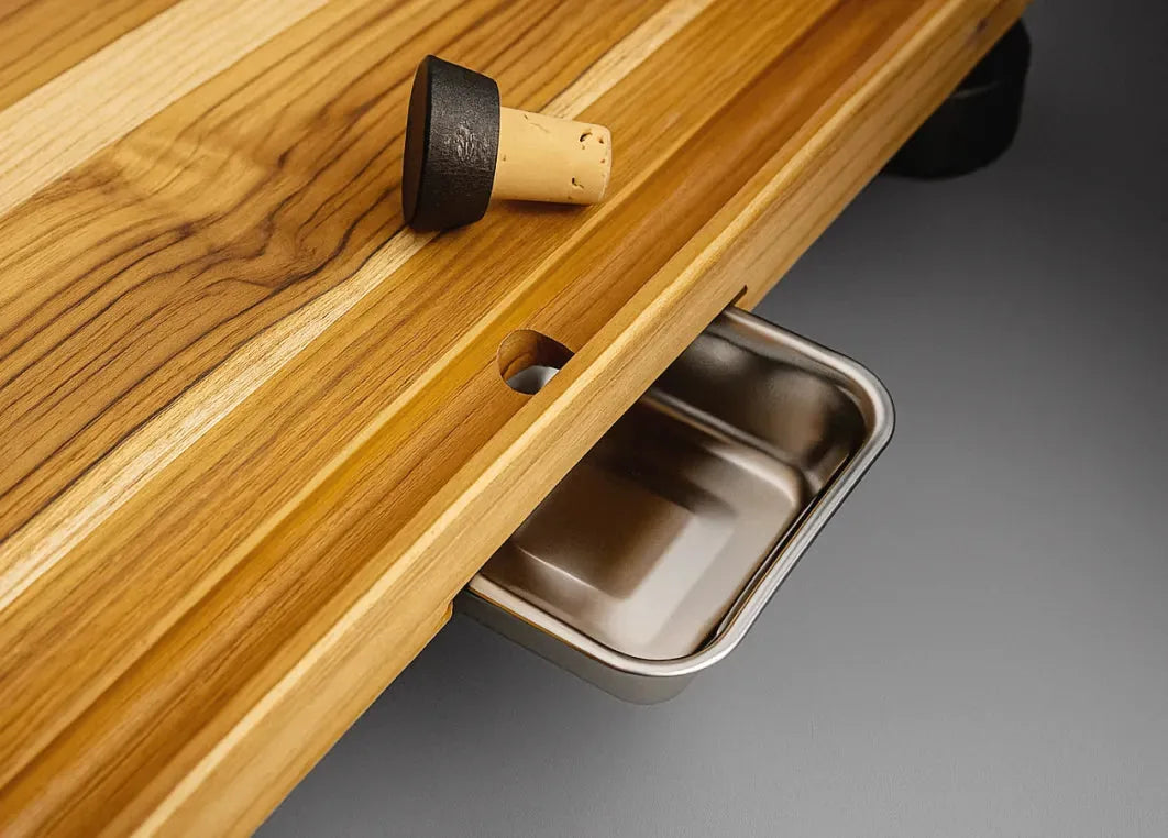 The angled juice groove and drop hole, with the cork beside it and the stainless-steel bowl underneath